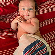 Augustus joined the competition — help win amazing prizes! baby, infant, towel, striped_blanket, red_background, lying_down, cute, chubby_cheeks, hands, face, portrait, skin, person, child, indoors, expression, eyes, smile, newborn, resting