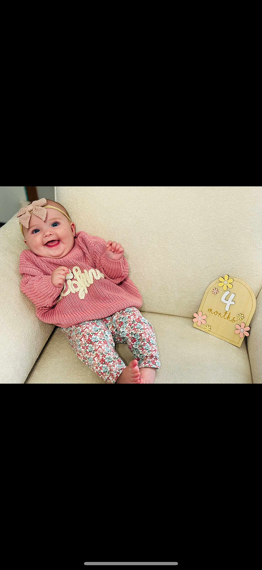 Leighnora joined the competition — help win amazing prizes! baby, smiling, pink_sweater, floral_pants, headband, bow, armchair, cream_color, wooden_sign, 4_months, decorative_flowers, happy, infant, cute, child, portrait, indoor, comfortable, clothing, young