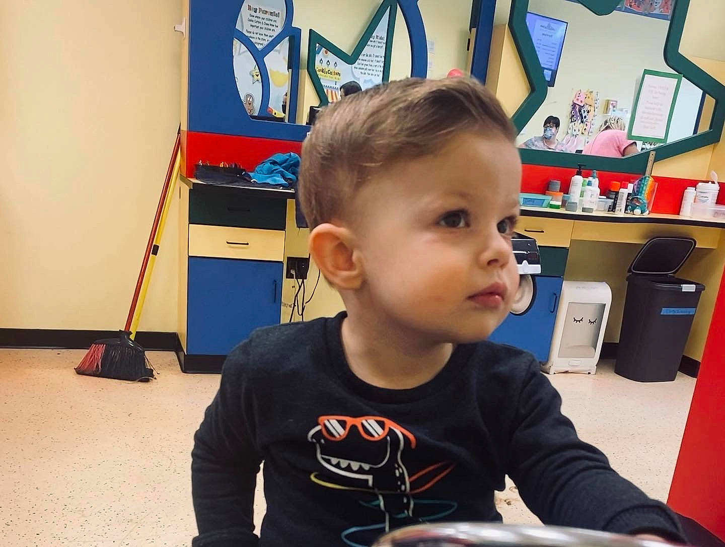 Flynn is registered to the contest to win money with this photo: art, baby, bookcase, chair, child, desk, flooring, fun, house, kindergarten, learning, person, personal_protective_equipment, play, recreation, room, shelf, sitting, t_shirt, toddler