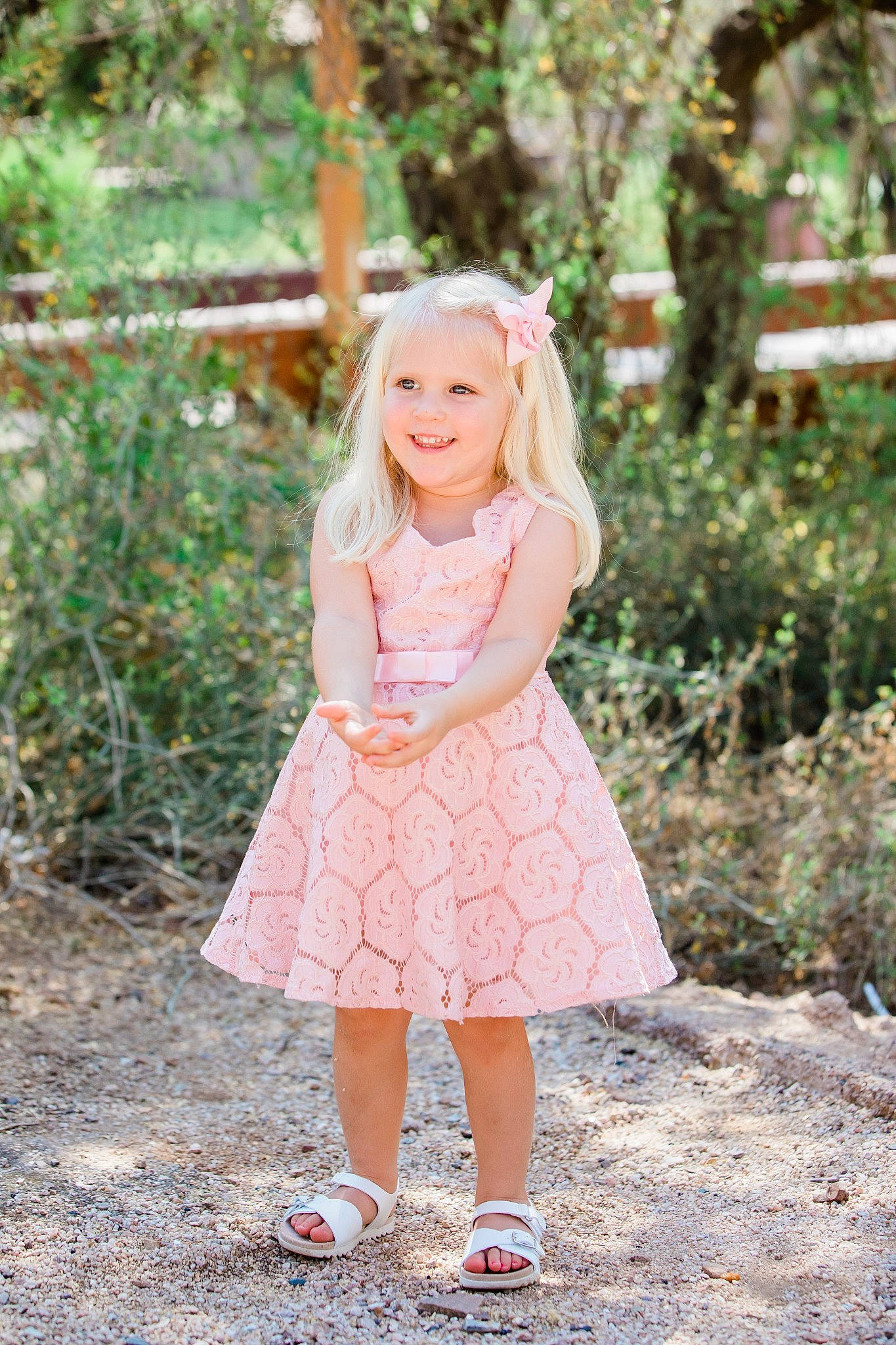 Harlow is registered to the contest to win money with this photo: baby_toddler_clothing, brown_hair, clothing, day_dress, dress, eye, forest, grass, happy, joy, outerwear, pattern, peach, people_in_nature, person, pink, plant, smile, toddler, tree
