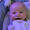 baby, infant, child, smiling, happy, portrait, face, eyes, open_mouth, bald, indoor, cushion, blanket, striped_fabric, clothing, seated, close_up, purple_lighting, cozy, photography