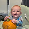 baby, child, high_chair, pumpkin, autumn, indoor, sitting, smiling, happy, face, portrait, infant, hands, food, vegetable, orange, stem, tray, clothing, home