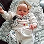 Scott joined the competition — help win amazing prizes! baby, infant, white_clothing, hoodie, blanket, couch, face, hand, foot, indoor, cute, child, person, soft_texture, pattern, cartoon_print, lying_down, cozy, home, comfort