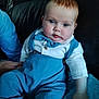 baby, blue_overalls, bow_tie, child, clothing, couch, cute, expression, face, hand, indoor, infant, leather, person, portrait, seated, sitting, soft_blanket, support, young_child