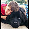 animal, black_dog, boy, casual_clothing, child, close_up, cozy, cuddling, cute, dog, domestic_animal, floor, friendship, happy, indoor, pet, portrait, short_hair, smiling, young