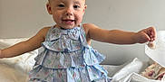 Blake is registered to the contest to win money with this photo: baby, barefoot, blue_dress, child, cute, dress, face, furniture, hand, happy, indoor, legs, pacifier, person, picture_frame, sitting, smiling, toddler, wall, young
