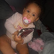 Winter joined the competition — help win amazing prizes! baby, bed, blanket, candid, child, clothing, cozy, curly_hair, cute, flash, indoor, infant, pacifier, phone, pink, portrait, sitting, stuffed_animal, toddler, toy