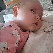 Ruby is registered to the contest to win money with this photo: baby, sleeping, pink_clothing, animal_print, indoor, blanket, cozy, person, head, face, child, soft_texture, couch, closeup, peaceful, resting, infant, cute, warm, comfort