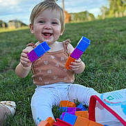 Alma participe au concours pour gagner de l'argent avec cette photo : toddler, child, grass, outdoor, smiling, toy, building_blocks, play, happy, person, sitting, topknot, casual_clothing, daylight, nature, fun, colorful, young_child, cute, leisure