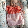 baby, infant, smile, blue_eyes, knitted_dress, pink, orange, tights, cushion, patterned, bunny_print, owl_print, soft_lighting, indoor, cute, child, portrait, lying_down, happy, cozy