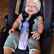 Hailee Grace is registered to the contest to win money with this photo: baby, baby_bottle, baby_clothes, bottle, car_seat, child, clothing, cute, face, hand, happy, headband, indoor, infant, person, seatbelt, sitting, smiling, toddler, wood_floor