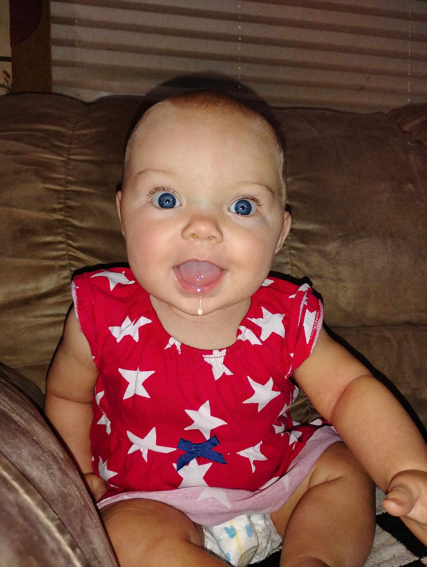 Hailee Grace joined the competition — help win amazing prizes! arm, baby, blue_eyes, child, clothing, couch, cute, diaper, drool, face, furniture, happy, head, indoor, infant, person, red_dress, sitting, smiling, stars