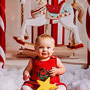 Hailee is registered to the contest to win money with this photo: baby, child, red_dress, yellow_star, rocking_horse, holiday, christmas, festive, toy, carpet, smiling, blue_eyes, white_tights, indoor, portrait, cute, decor, background, holiday_theme, seasonal
