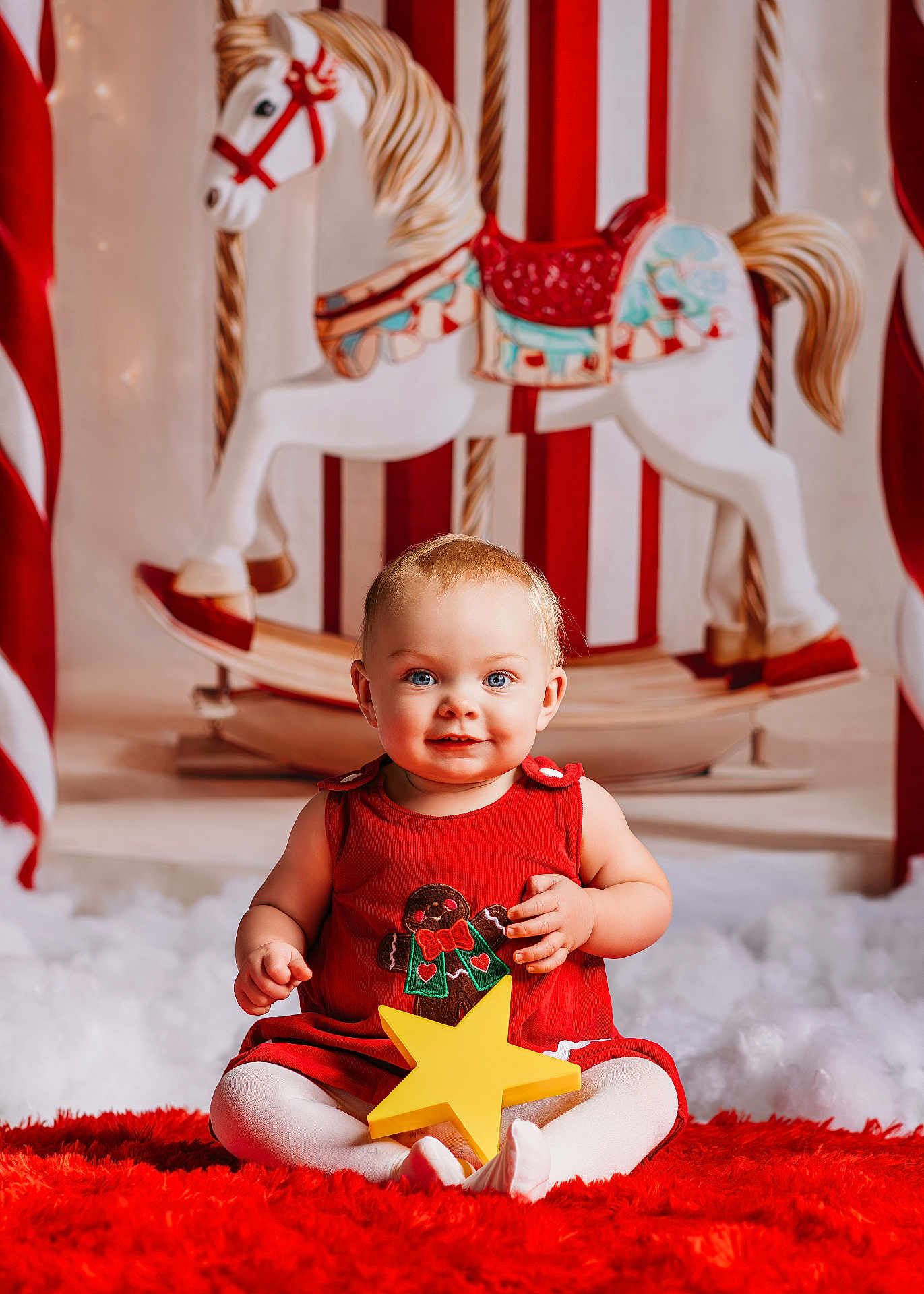 Hailee is registered to the contest to win money with this photo: baby, child, red_dress, yellow_star, rocking_horse, holiday, christmas, festive, toy, carpet, smiling, blue_eyes, white_tights, indoor, portrait, cute, decor, background, holiday_theme, seasonal