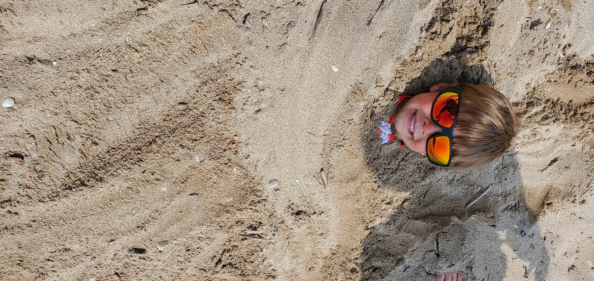 Harry is registered to the contest to win money with this photo: adventure, bedrock, concrete, eyewear, foot, fun, grass, joy, landscape, person, personal_protective_equipment, recreation, rock, sand, shadow, slope, soil, wood