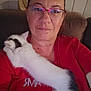 Sid participe au concours pour gagner de l'argent avec cette photo : person, glasses, red_shirt, kitten, cat, white_cat, black_spots, couch, indoor, close_up, face, pet, cozy, relaxed, home, furniture, comfort, affection, resting, animal