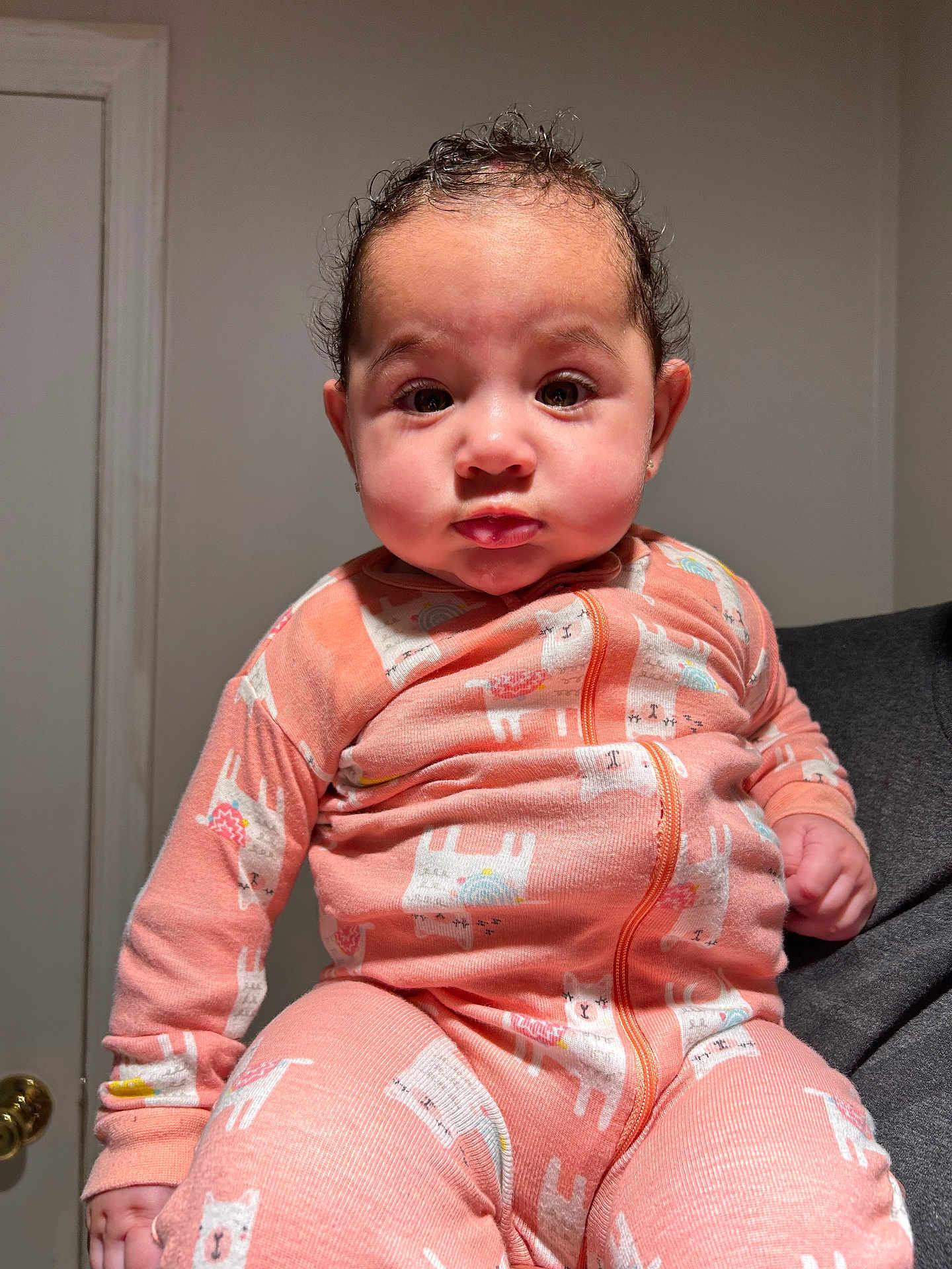 Andrea joined the competition — help win amazing prizes! baby, child, infant, onesie, pink_clothing, llama_print, indoor, door, doorknob, curly_hair, portrait, cute, chubby_cheeks, expression, pout, person, human, holding, sleeves, front_zipper