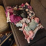 baby, cat, couch, blanket, sleeping, indoor, floor, bag, footwear, pink_socks, romper, tabby_cat, furniture, cozy, resting, wooden_floor, striped_ottoman, patchwork_blanket, pet, child