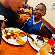 Samir joined the competition — help win amazing prizes! child, burger, food, restaurant, smile, happy, table, plate, fried_food, hot_sauce, casual_dining, meal, fork, knife, person, blue_jersey, indoor, dining, excited, face