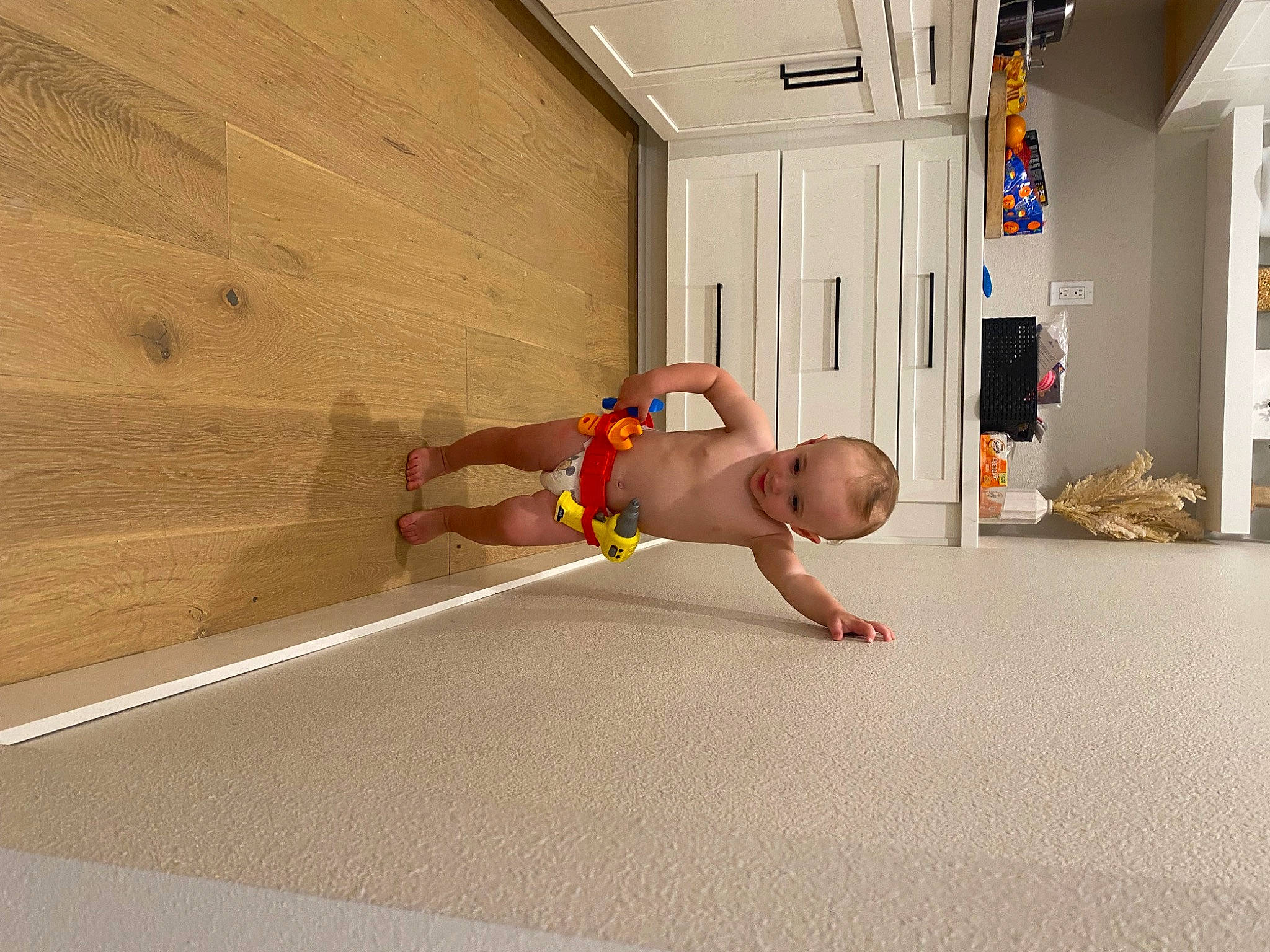 Jaxon is registered to the contest to win money with this photo: barechested, bed, comfort, crawling, door, floor, flooring, fun, hardwood, house, houseplant, human_leg, knee, leisure, person, recreation, room, shorts, thigh, wood