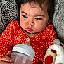 baby, bottle, milk, polka_dot, orange_clothing, blanket, hand, face, infant, cozy, texture, couch, portrait, indoors, young_child, sleepy, expression, holding, closeup, warm