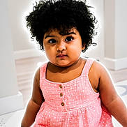Anika Yenkarla joined the competition — help win amazing prizes! toddler, child, girl, curly_hair, pink_dress, polka_dot, indoor, portrait, cute, young_child, face, expression, sitting, minimalist_background, soft_lighting, curious, eyes, skin, hair, buttoned_dress