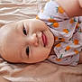 baby, infant, smile, onesie, orange_pattern, blanket, soft_texture, cute, lying_down, face, child, happy, skin, young, adorable, closeup, person, head, eyes, mouth