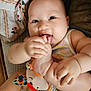 baby, infant, foot, hand, plush_toy, colorful, chewing, cute, chubby, blanket, fabric, sitting, indoors, skin, person, child, playful, smiling, closeup, comfort
