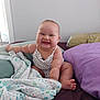 baby, smiling, child, infant, bed, pillow, blanket, polka_dot_clothing, cute, happy, indoor, person, sitting, chubby, skin, foot, hand, face, room, light