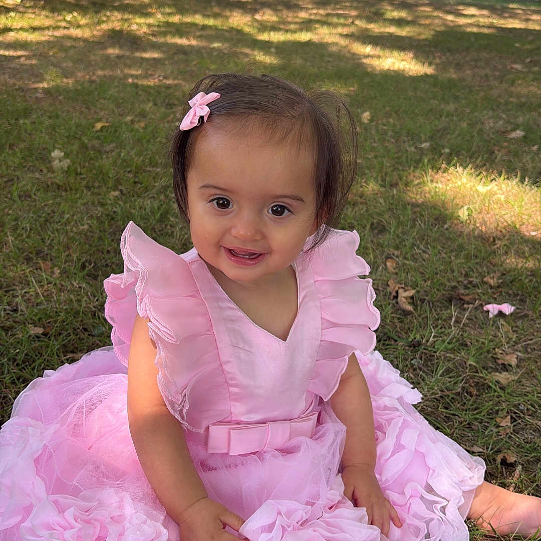 Ginger participe au concours pour gagner de l'argent avec cette photo : baby, bow, child, cute, daylight, grass, happy, nature, outdoor, park, pink_dress, playful, portrait, shade, sitting, smiling, sunlight, toddler, trees, young_child