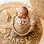 newborn, baby, sleeping, swaddled, basket, plush_toy, teddy_bear, woven_mat, beige, soft_fabric, wooden_letters, fairy_lights, cozy, peaceful, portrait, infant, cute, decor, nursery, resting