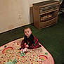 Aurora is registered to the contest to win money with this photo: baby, infant, child, play_mat, blanket, toy, plush_toy, carpet, green_carpet, heater, vintage_heater, wall, power_socket, dress, plaid_dress, sitting, looking_up, face, eyes, indoor