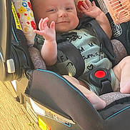 Kehlani is registered to the contest to win money with this photo: baby, car_seat, child, smiling, waving, infant, seatbelt, floral_pattern, wooden_floor, sunlight, happy, cute, indoors, clothing, person, face, hand, foot, safety, seat