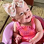 Kehlani is registered to the contest to win money with this photo: baby, child, smiling, pink_clothing, bow, headwear, purple_seat, wooden_floor, porch, infant, happy, cute, sitting, person, indoors, closeup, skin, face, hands, feet