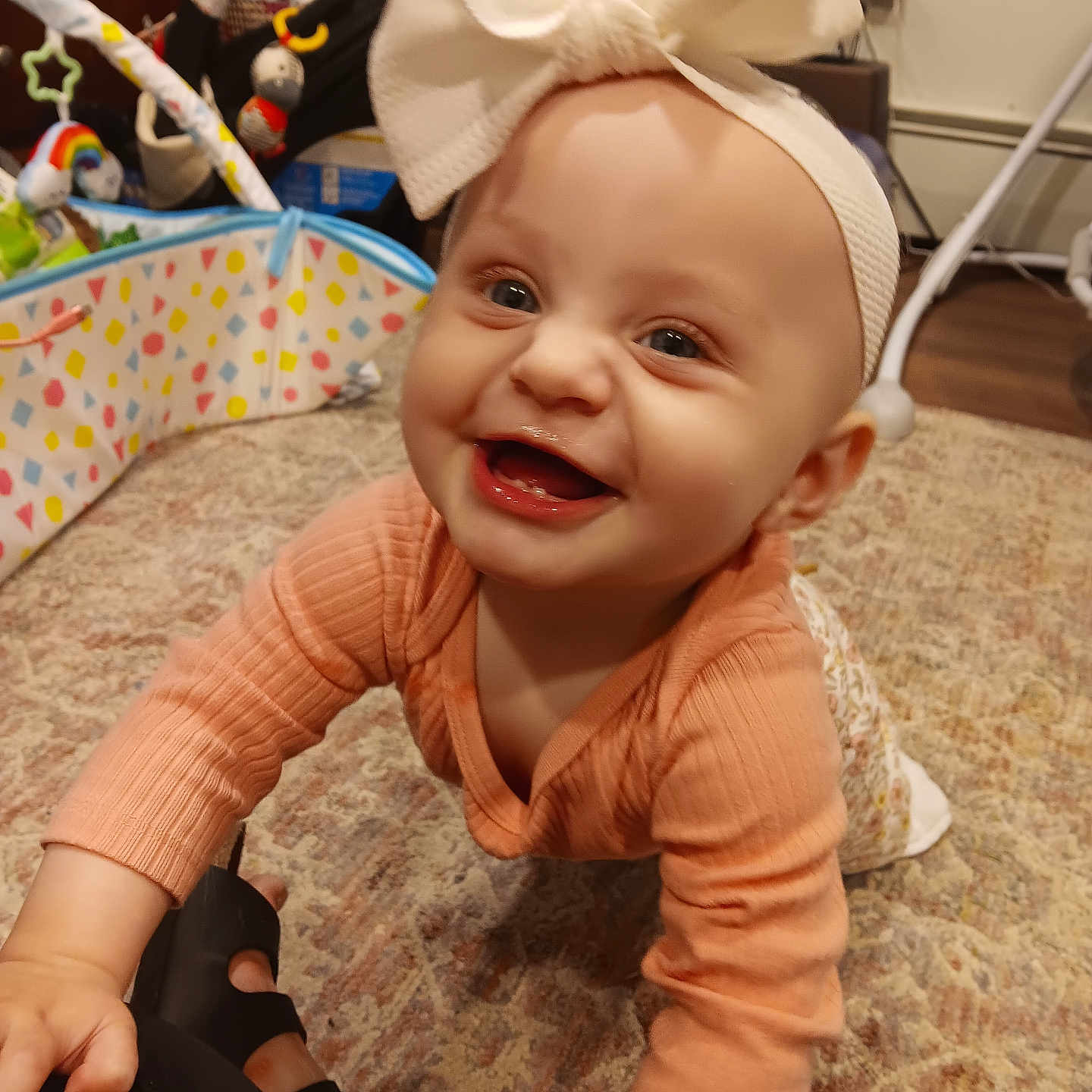 Bobi joined the competition — help win amazing prizes! baby, bright_eyes, carpet, child, crawling, cute, face, floor, happy, headband, home, indoor, infant, long_sleeve_shirt, person, playtime, smiling, toddler, toy, white_bow