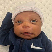 Ayden joined the competition — help win amazing prizes! baby, infant, face, hat, clothing, jacket, nike, blue, skin, eyes, mouth, expression, closeup, portrait, newborn, texture, background, indoor, cute, child