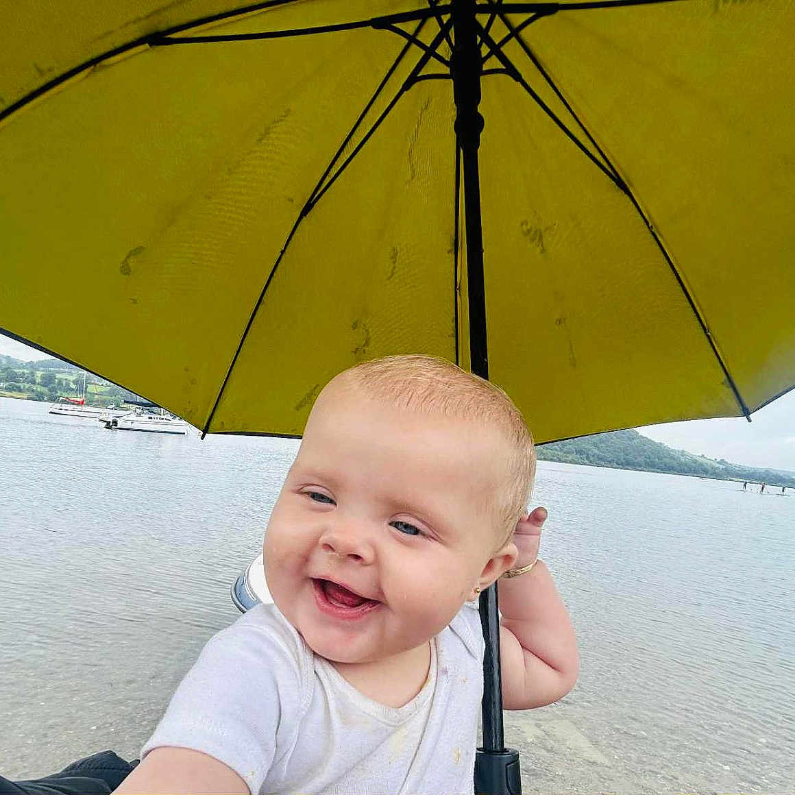 Veronica-Jade is registered to the contest to win money with this photo: baby, boats, child, cloudy, cute, happy, hill, lake, nature, outdoor, person, portrait, scenic, sky, smiling, summer, umbrella, vacation, water, yellow