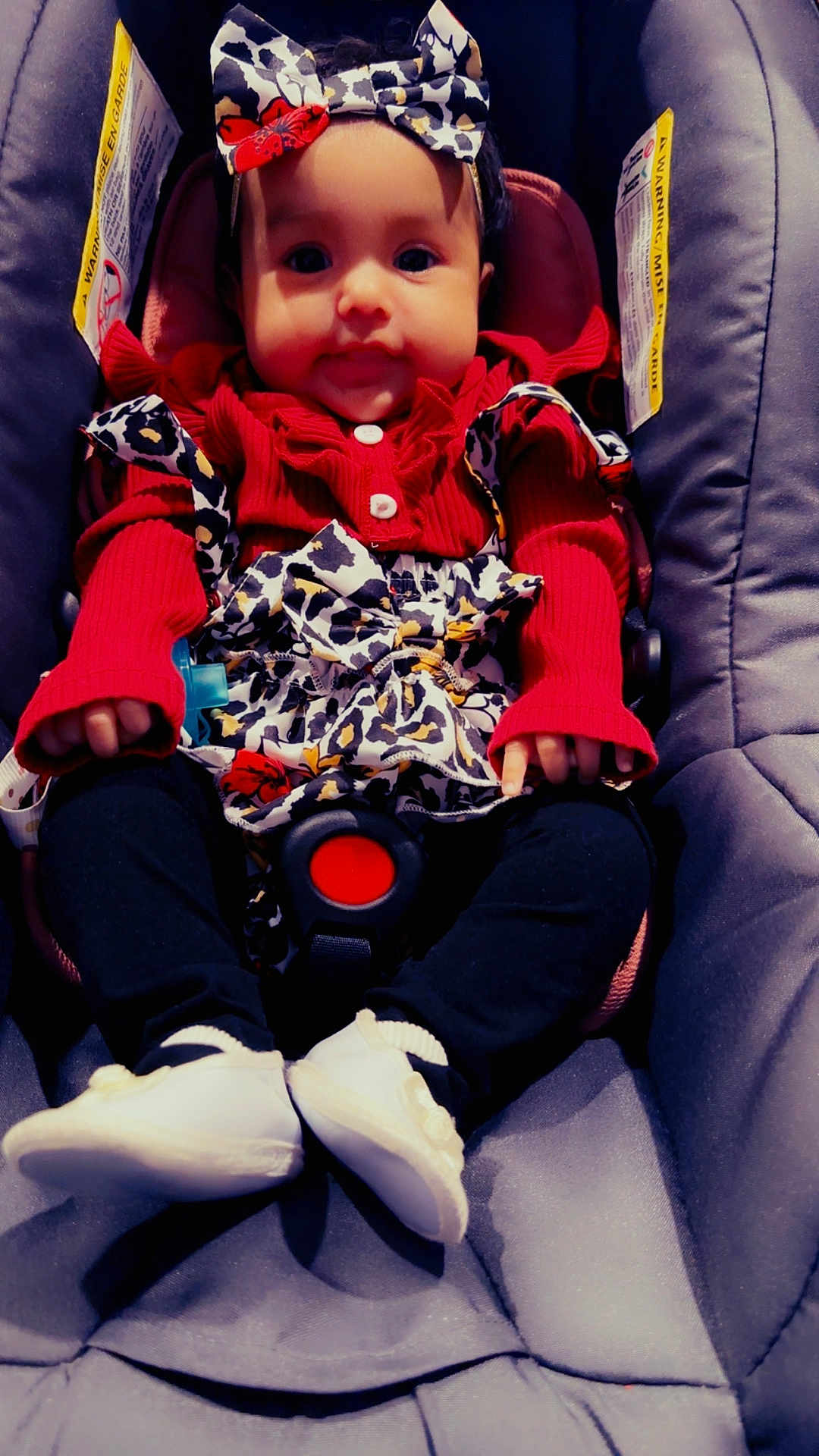 Edilia joined the competition — help win amazing prizes! baby, child, car_seat, red_clothing, headband, leopard_print, white_shoes, black_pants, infant, cute, smile, sitting, indoors, clothing, person, baby_accessories, seatbelt, face, young_child, portrait