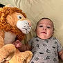 baby, infant, plush_toy, lion, stuffed_animal, bed, bedding, clothing, onesie, child, cute, soft, toy, indoor, portrait, lying_down, person, young_child, face, expression