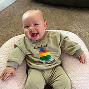 Mckinley joined the competition — help win amazing prizes! baby, infant, smiling, drooling, shirt, ring_graphic, onesie, pillow, boppy_pillow, carpet, couch, indoor, sitting, happy, chubby_cheeks, hand, legs, cute, young_child, portrait