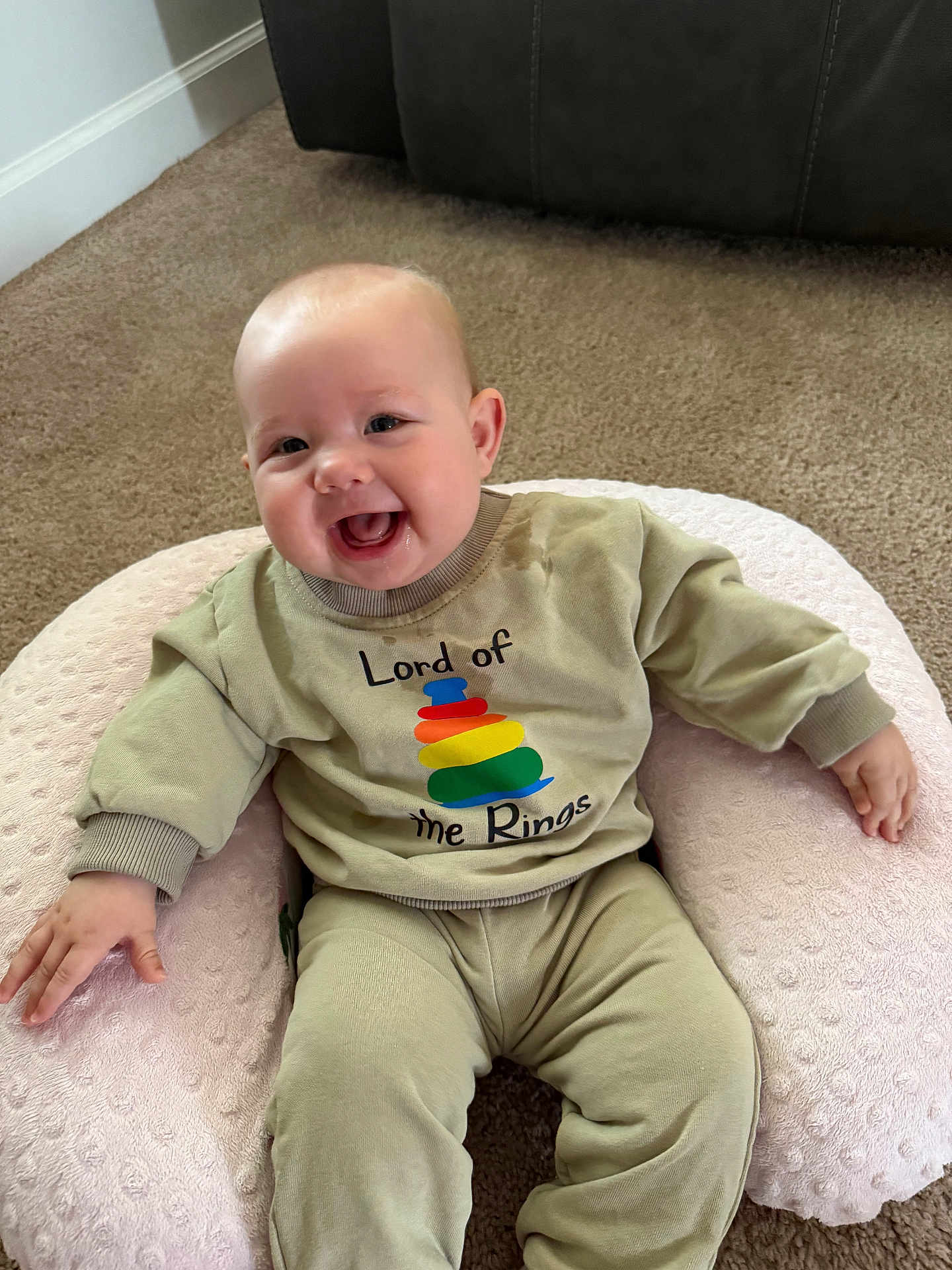 Mckinley joined the competition — help win amazing prizes! baby, infant, smiling, drooling, shirt, ring_graphic, onesie, pillow, boppy_pillow, carpet, couch, indoor, sitting, happy, chubby_cheeks, hand, legs, cute, young_child, portrait