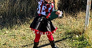 Gemini is registered to the contest to win money with this photo: black_skirt, boots, chains, child, clown_costume, costume, daylight, face_paint, fence, fun, grass, hat, outdoor, person, play, playground, posing, red_tights, smile, swing