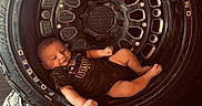 Bodie is registered to the contest to win money with this photo: baby, baby_boy, black, black_rhino, camouflage, clothing, cute, indoors, infant, newborn, portrait, posing, resting, round, rubber, small, stacked, tire, vehicle_part, wheel