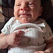 Bodie joined the competition — help win amazing prizes! baby, infant, smile, onesie, clothing, carrot_pattern, avocado_pattern, hand, fist, face, cheeks, lying_down, quilt, blanket, indoor, cute, skin, head, person, portrait