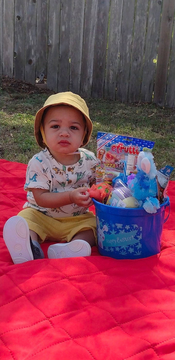Marcellus joined the competition — help win amazing prizes! baby, baby_toddler_clothing, child, event, fence, fun, grass, happy, hat, headwear, holiday, lap, leisure, person, plastic, play, recreation, sitting, sun_hat, toddler