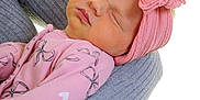 Ocean is registered to the contest to win money with this photo: baby, newborn, sleeping, pink, headband, bow, arm, adult, sleeve, bracelet, closeup, portrait, child, infant, soft_fabric, holding, skin, cute, peaceful, cozy