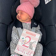 Ocean joined the competition — help win amazing prizes! baby, infant, sleeping, car_seat, pink_hat, pom_poms, onesie, spotted_clothing, milestone_card, text_card, bunny_illustration, flowers, newborn, cute, child, seatbelt, soft_lighting, portrait, close_up, indoors