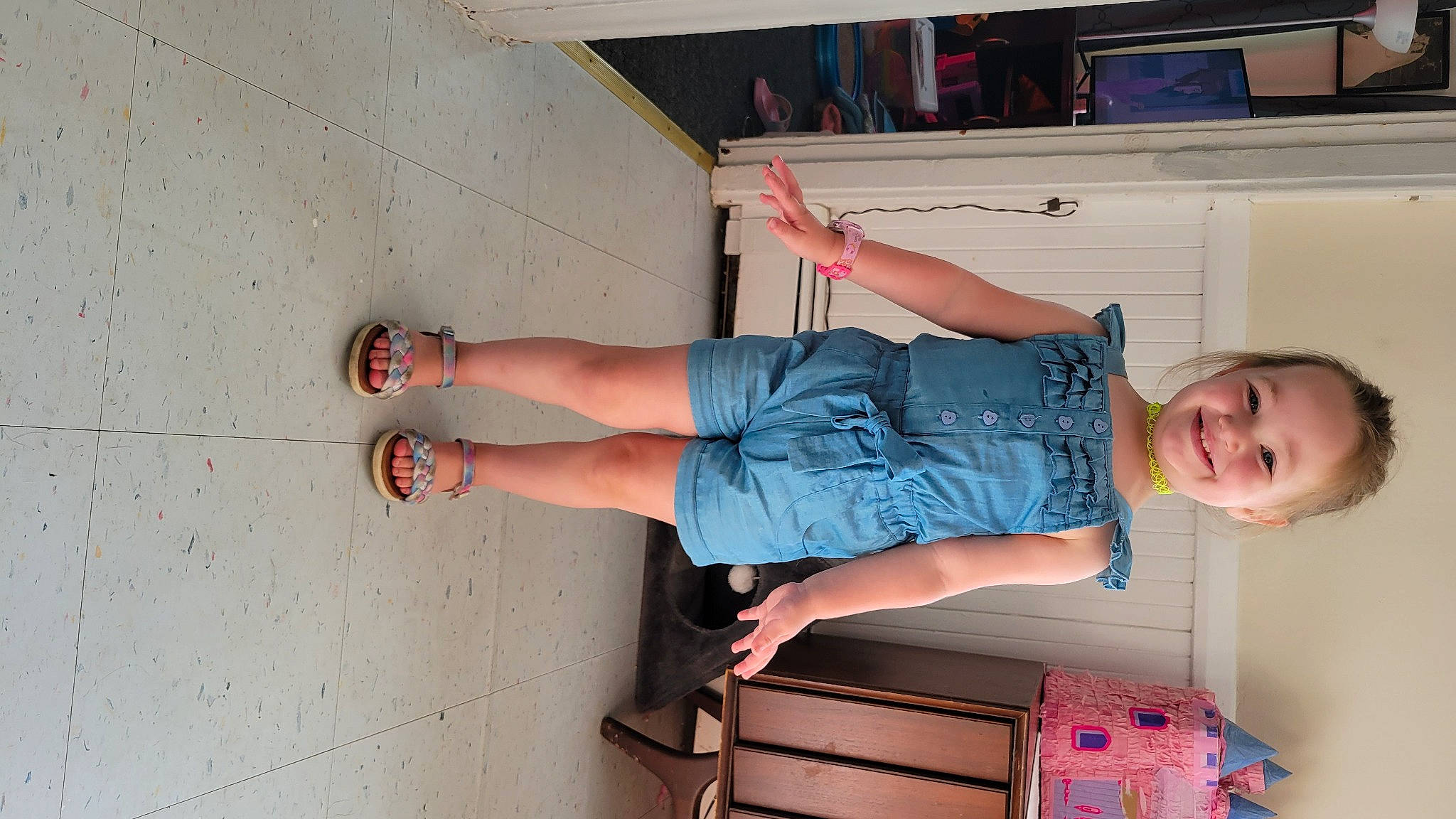 Guinevere is registered to the contest to win money with this photo: baby_toddler_clothing, calf, comfort, elbow, finger, foot, fun, hand, human_body, human_leg, joint, joy, knee, leg, orange, person, room, sandal, smile, standing