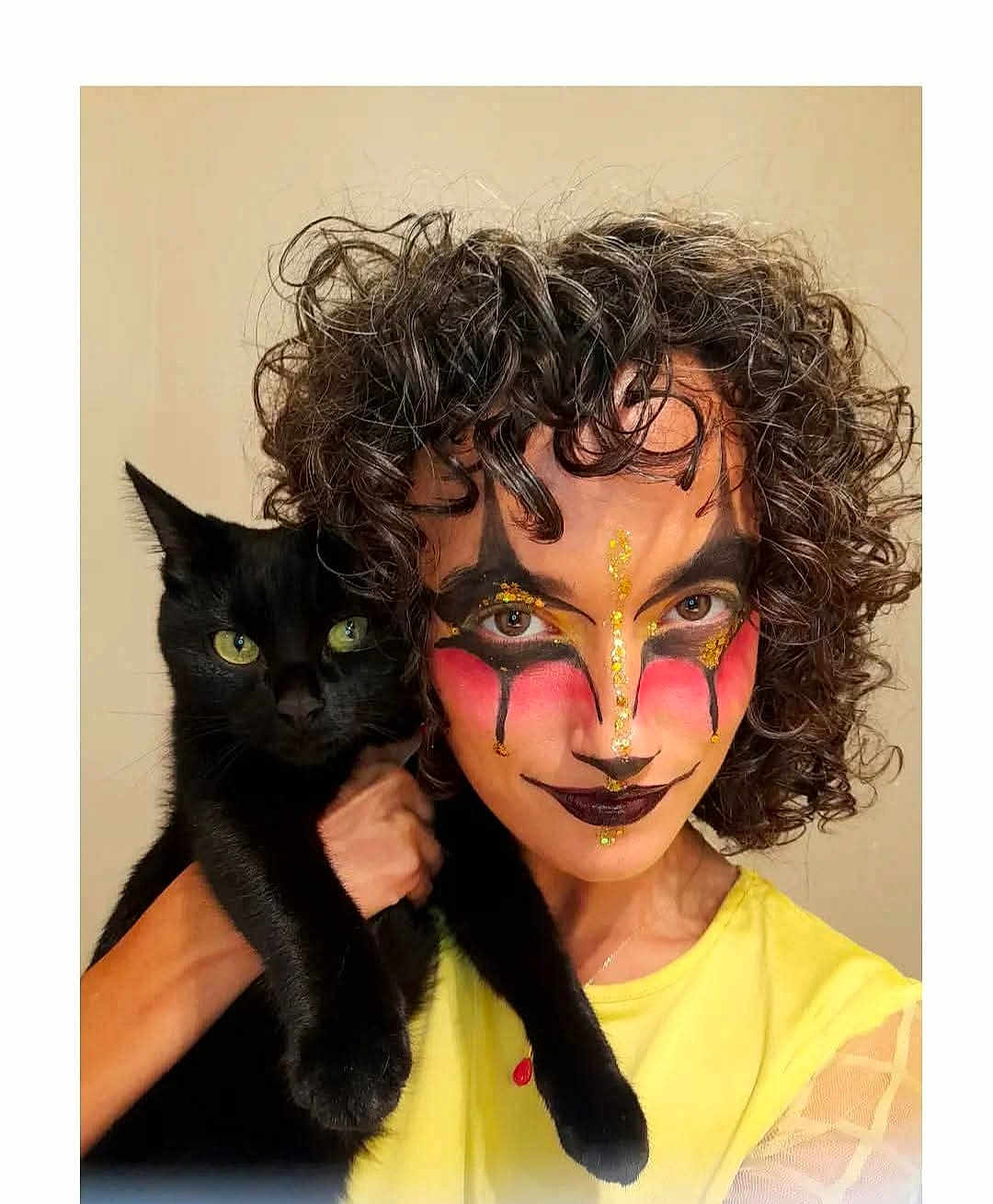 Lana participe au concours pour gagner de l'argent avec cette photo : person, cat, black_cat, curly_hair, face_paint, makeup, yellow_shirt, pet, animal, portrait, indoor, green_eyes, holding, looking_at_camera, close_up, expression, creative_makeup, costume, human, feline