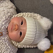 Meï-Linh participe au concours pour gagner de l'argent avec cette photo : baby, child, face, hat, pom_poms, knit, white, jacket, fluffy, clothing, portrait, smile, cute, infant, warm, indoor, soft_texture, lying_down, person, headwear